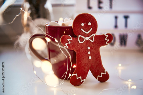 Homemade gingerbread cookie with festive bokeh decor on Let it snow background. Christmas decorations with hot drink and marshmallows. Aesthetic Christmas atmosphere, home coziness, warmth concept