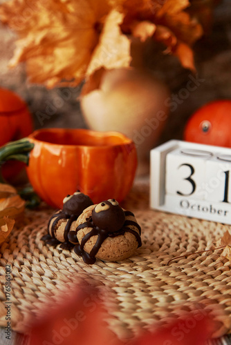 Autumn Halloween cookies in shape of spider and cup of tea in shape of pumpkin near 31 of October on calendar
