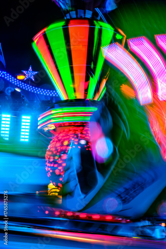 Bewegliche Lichter eines Karussells mit bunter Beleuchtung. Verschwommene Lichtspuren und -flecken, aufgenommen mit Langzeitbelichtung auf einem Jahrmarkt in Deutschland