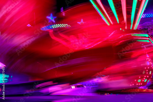 Bewegliche Lichter eines Karussells mit bunter Beleuchtung. Verschwommene Lichtspuren und -flecken, aufgenommen mit Langzeitbelichtung auf einem Jahrmarkt in Deutschland
