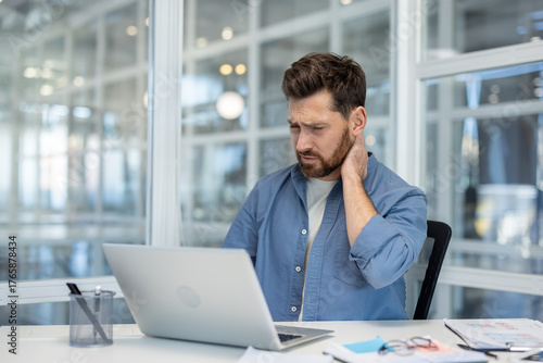 Konstfotografi Man suffering from severe neck and shoulder pain while working on his laptop at