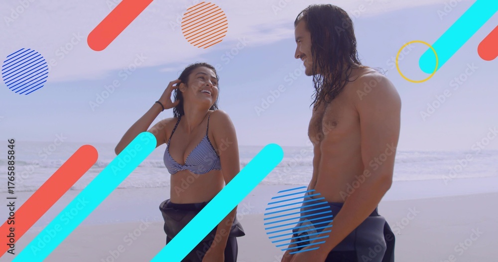 Naklejka premium Smiling couple exchanging glances on wet sand, with striped bikini top, wetsuit pants and waves
