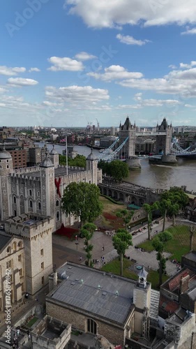 Cinematic 4K drone footage of the Tower of London and Tower Bridge, showcasing the historic fortress, River Thames, and the vibrant London skyline under clear summer light.