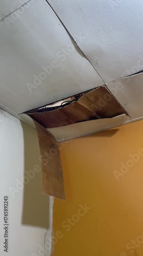 Ceiling damage visible in the corners of the room, revealing rotting wood or plaster peeling from the structure. Home problems include water infiltration and poor maintenance.