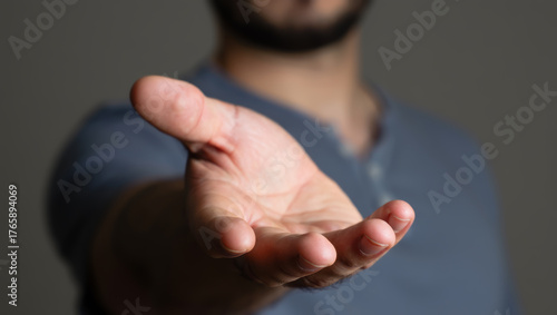 Close-up of a man's hand extended forward, symbolizing help, support, or an invitation to interact against a blurred background