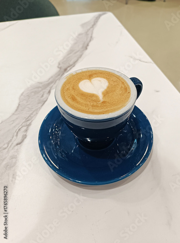 Cappuccino in a blue ceramic mug on a white table