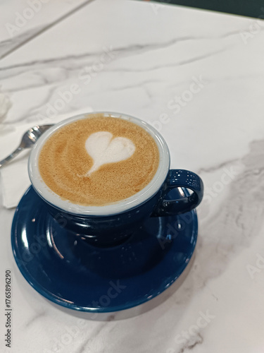 Cappuccino in a blue ceramic mug on a white table