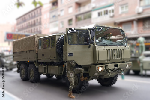 Military vehicle parked during a public event in an urban setting with soldiers nearby