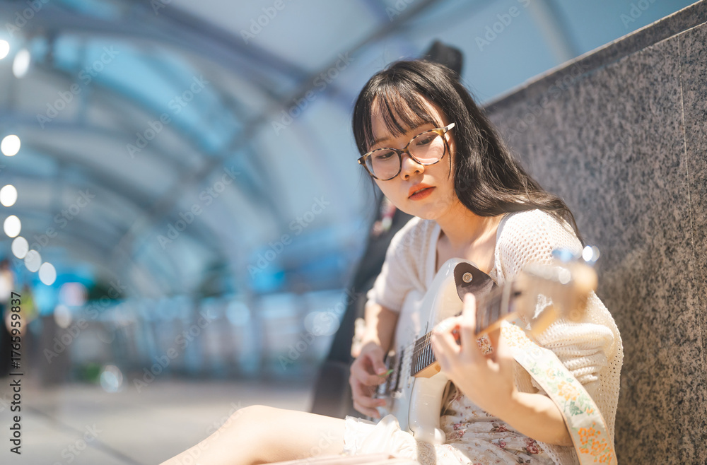 Fototapeta premium Gen z asian woman playing electric guitar busking street music at outdoor night city wearing y2k fashionable style