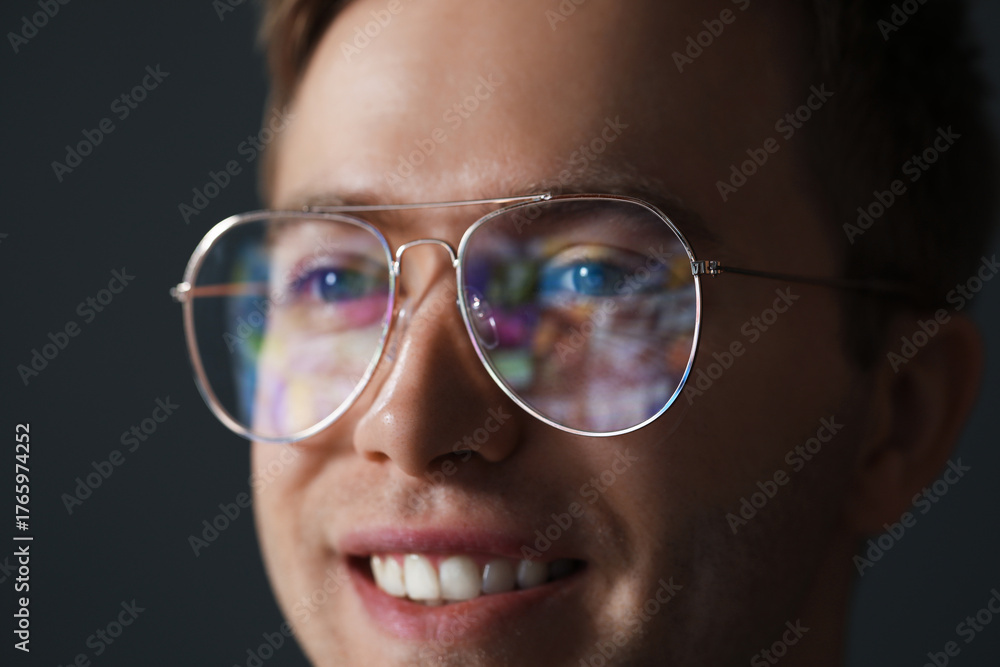 Fototapeta premium Smiling man wearing glasses with reflection on dark background, closeup