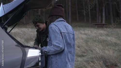 Couple unpacking car trunk for hiking trip in nature