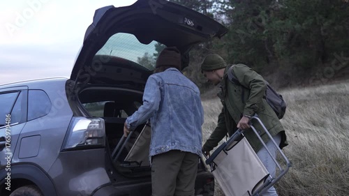 Couple unpacking car trunk for hiking trip in nature