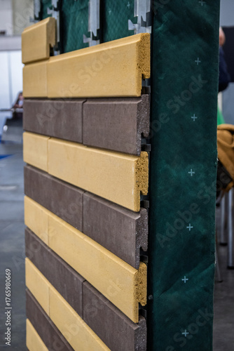 Tableau sur toile Close-up of a modern ventilated facade system showcasing alternating beige and brown cladding panels being installed over a green moisture barrier