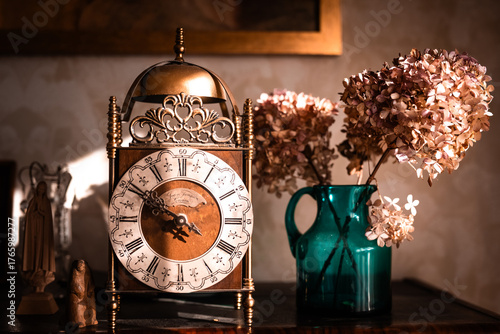 
an old gold clock on a shelf with a vase of hydrangeas