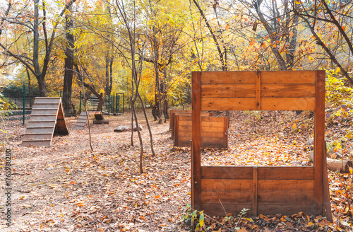 Empty outdoor dog training area in a sunny fall park with wooden equipment