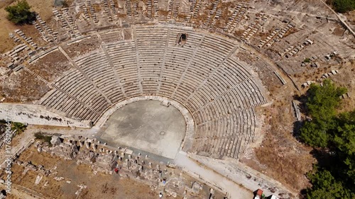 Aerial top view of the ancient amphitheater in Bodrum, Turkey. Historic stone structure and semicircular design showcase ancient architecture under bright sunlight.
