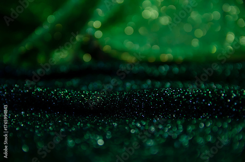 A bright holiday template. Background for congratulations. Green and black shiny fabric. A screen saver with a Bokeh.