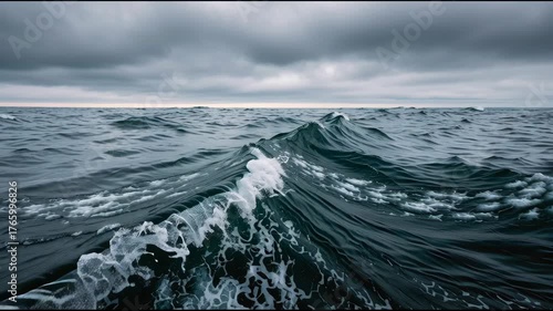 Dramatic dark stormy ocean with powerful rough sea wave cresting. Moody water under turbulent sky captures raw, untamed energy of wild nature seascape