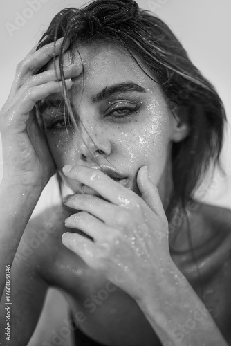 Studio close-up of a beautiful woman with natural makeup, wet hair, and sparkling glitter on her skin. perfect for beauty, skincare, fashion, or editorial concepts.