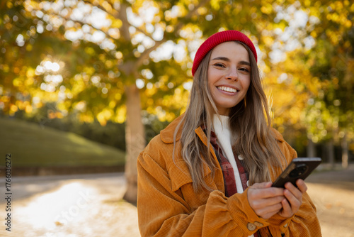 young attractive blond woman walking in autumn park, stylish , smiling, using smartphone