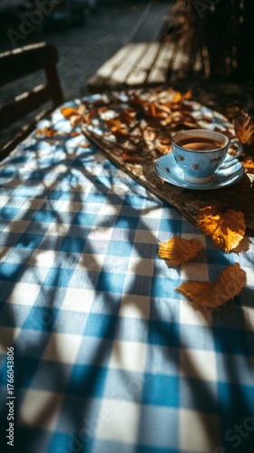 Coffee and Autumn Leaves on a Blue Checkered Tablecloth in a Sunny Outdoor Se...