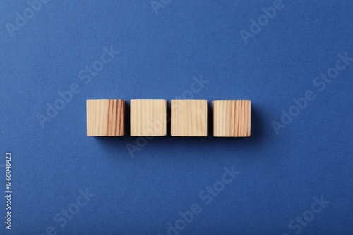 Wooden cubes on blue background, top view