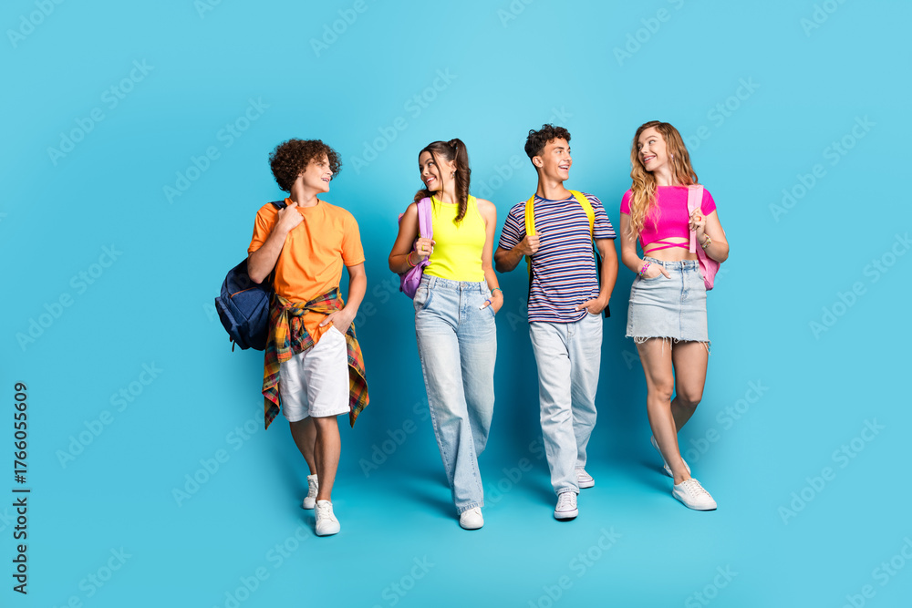 Fototapeta premium Funny fresh friends walk together in bright outfits against a blue backdrop