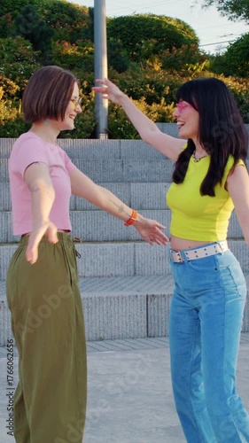 Glad women give high five and hug as roller skating in park