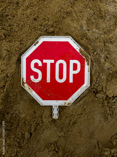 Red stop sign lying on sand — warning symbol representing caution, restriction, and safety concept. Traffic sign on ground background for risk, danger, or alert message themes