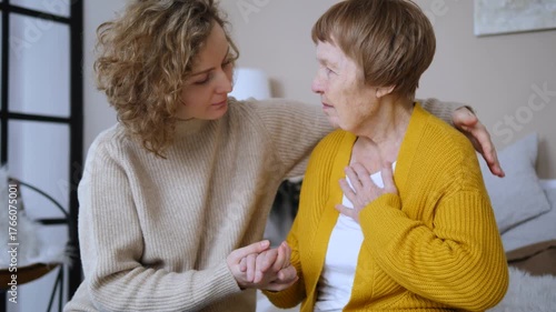 Anxious young woman comforting her upset elderly mother, showing empathy and support while holding her hand and talking to her, expressing love and understanding during a difficult moment