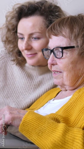 Young woman showing her grandmother how to use a laptop. Helping the elderly person learn new technology while spending quality time together. Promoting intergenerational bonding and digital literacy