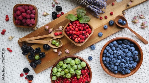 Delicious mix of fresh summer berries on a wooden board, including blueberries, wild strawberries, raspberries, gooseberries, redcurrants, and blackberries for a healthy antioxidant rich diet