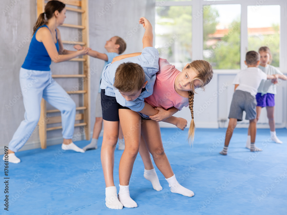 Fototapeta premium Purposeful engrossed children train during krav maga training session and work out basic elements with partner. Martial arts school, melee