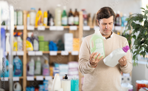 Quadro em tela European holds cleaning products in plastic packages against the background of shelving with household chemicals