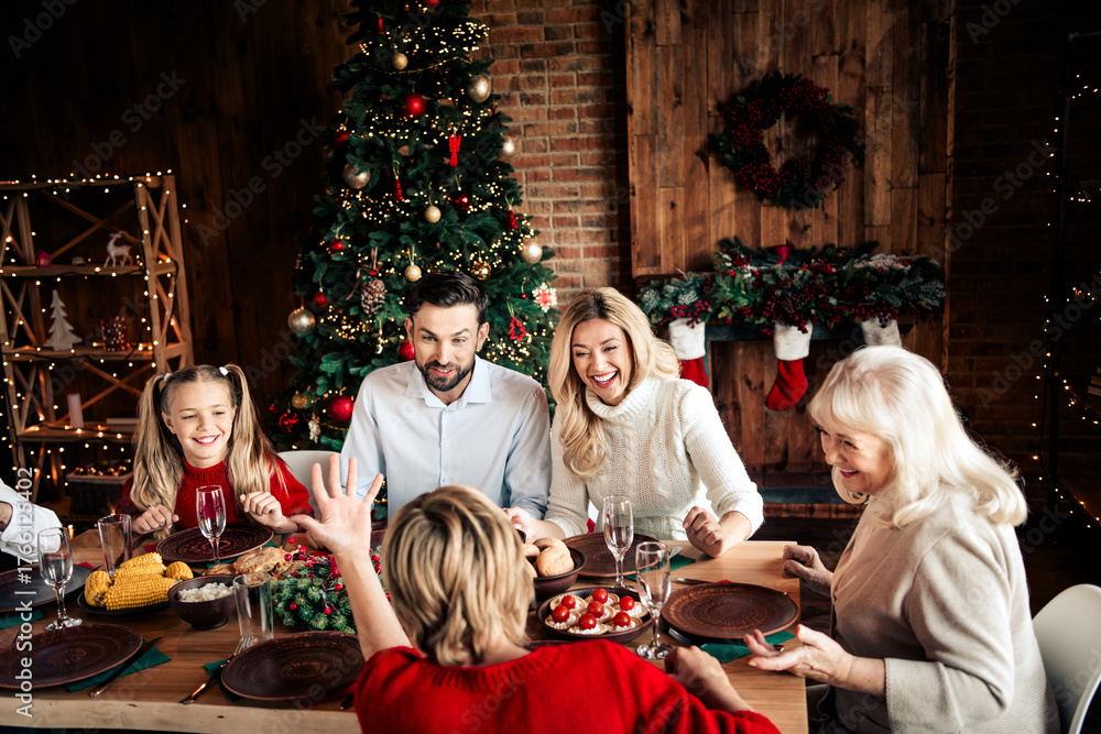 Naklejka premium Family Christmas dining scene around a festive table with a decorated tree and warm home ambiance