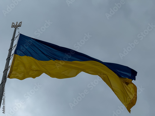 Ukrainian national flag with trident emblem waving against cloudy sky – symbol of freedom and resilience