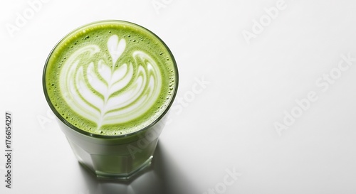 A matcha latte with intricate latte art in a clear glass