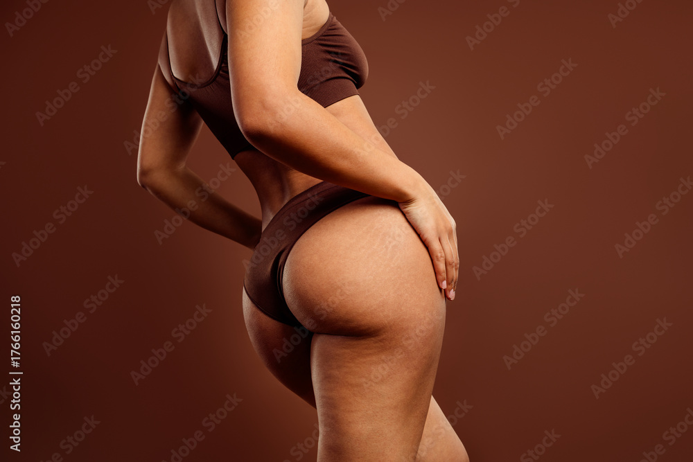 Obraz premium Beautiful woman in stylish brown activewear on a matching seamless background embracing her natural beauty and shape