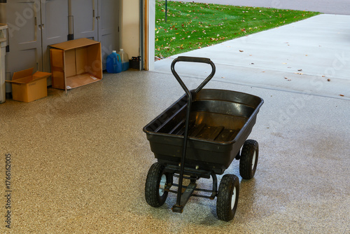 A black garden wagon cart on the epoxy covered floor of the garage.