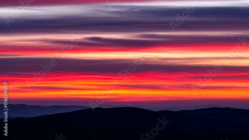 Vibrant sunset over rolling hills with colorful clouds and tranquil landscape