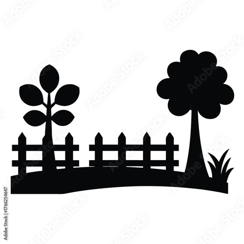 Silhouette of a picket fence with a small tree and a large tree in a garden