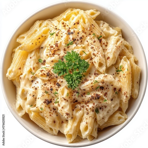 Top down view of creamy penne pasta served in a white bowl garnished with fresh parsley and sprinkled dark spices