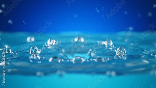 Close-up shot of water splashing and creating ripples in clear blue liquid, dynamic liquid surface, fluid motion