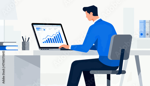 A man is sitting at a desk with a laptop open in front of him. He is working on a project and he is focused