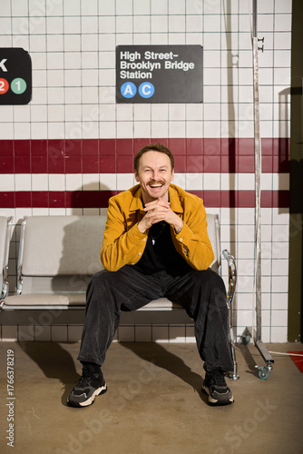 Man sitting at subway station with a cheerful expression