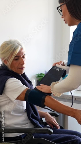 Medical professional using a tonometer to measure the blood pressure of a senior woman in a wheelchair during a routine check up at a clinic, ensuring proper cardiovascular health monitoring