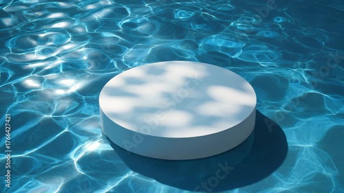 White cylindrical pedestal immersed in rippled blue water displaying sunlit reflections on its surface and the surrounding liquid