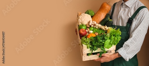 Panel kuchenny z motywem Male farmer with box of vegetables and fruits on beige background with space for text, closeup
