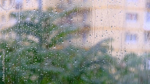 Rain drops running down the window surface. Heavy summer rain outside. Strong wind and rain drops falling on glass window