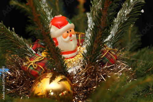 Santa Claus Figurine and Gold Ornaments in Frosted Fir Branches Close-up